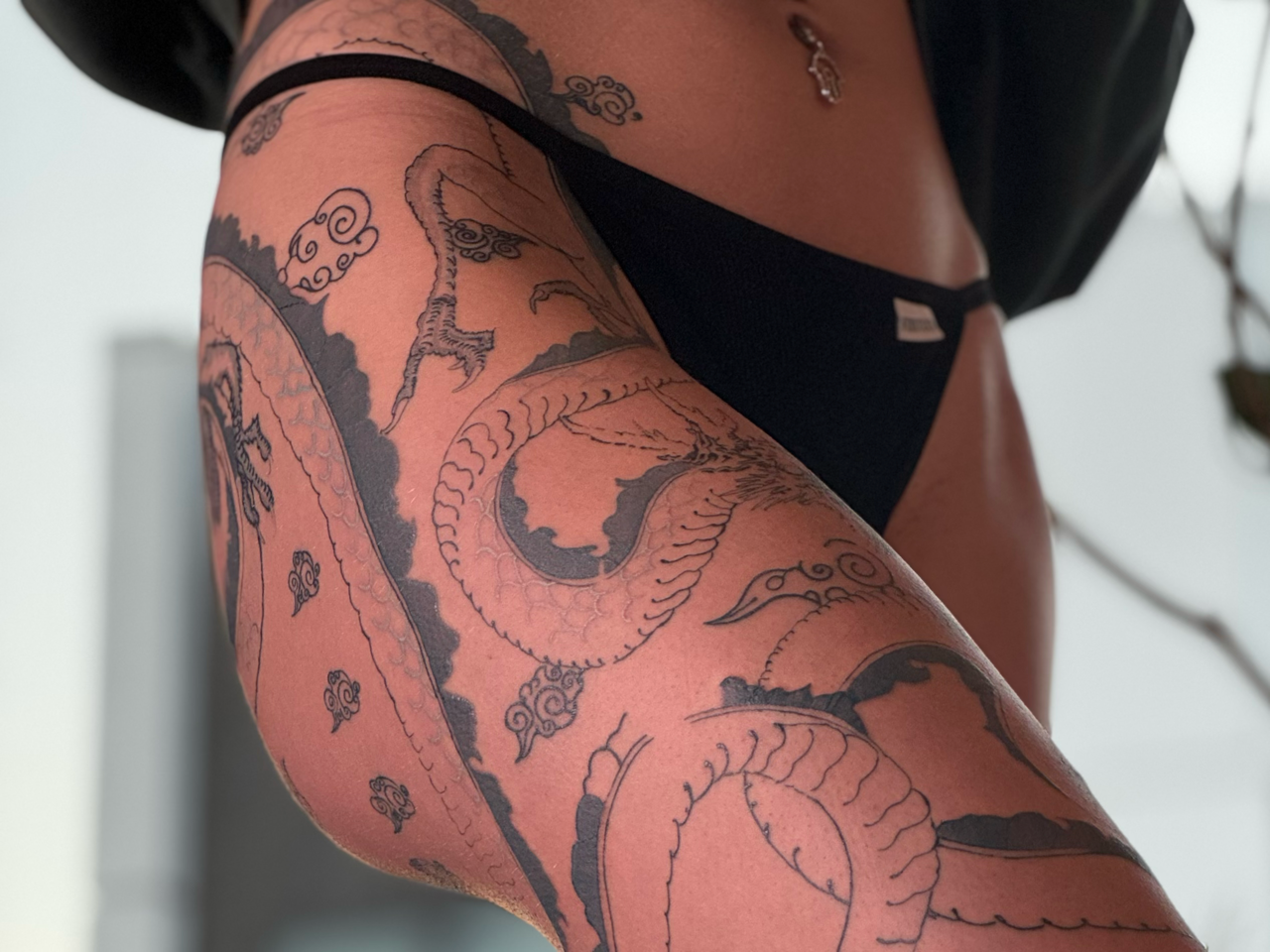 Fine-line dragon winding from hip to knee through stylized Korean cloud bands