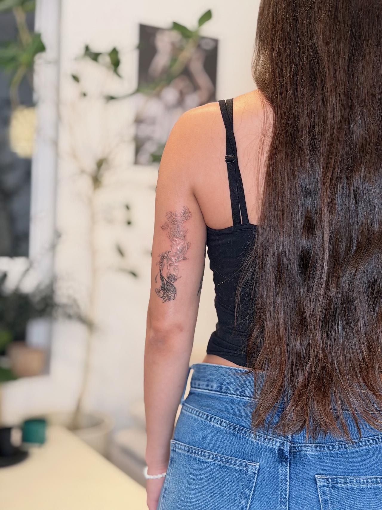 Flowing botanical cascade in fine line down the back of the upper arm