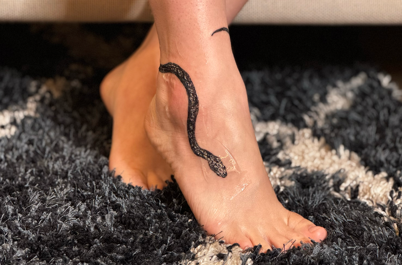 Black serpent winding over the ankle and onto the top of the foot